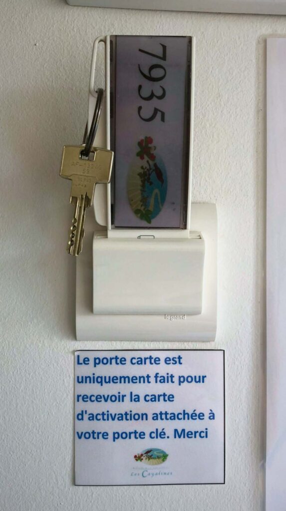 Room key slot and French instructions on the wall of a Les Cayalines Résidence Hôtelière guest room