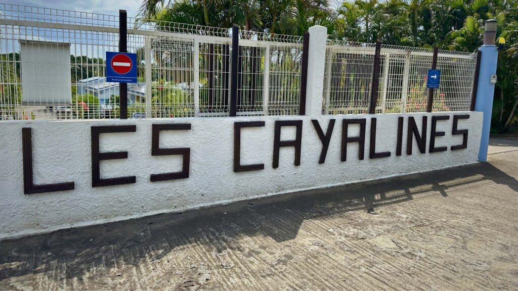 The Les Cayalines entrance sign photographed from street level on a bright Martinique afternoon