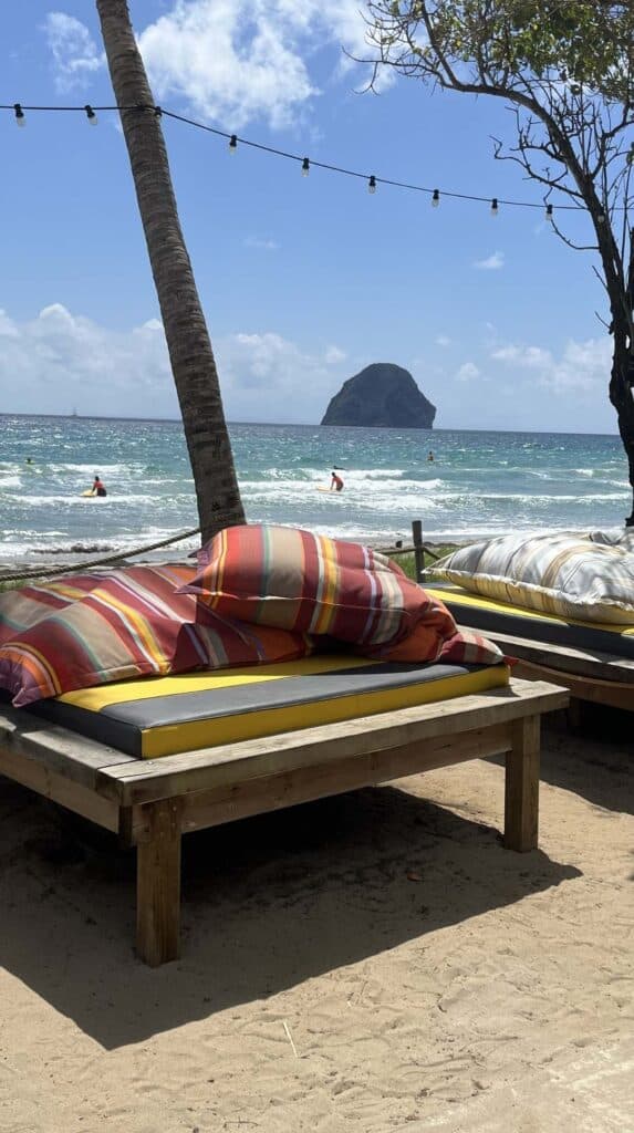 Colorful striped cushions on a beachside daybed with Diamond Rock in the background during a Martinique tour
