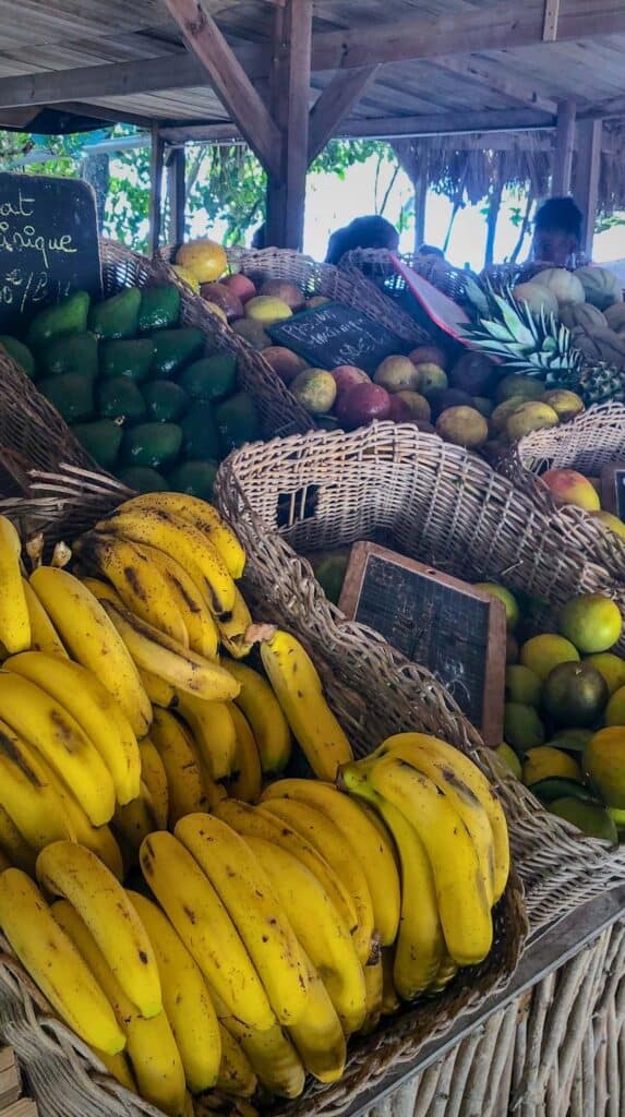 Colorful tropical fruit market stall piled high with bananas and mangoes in Martinique island