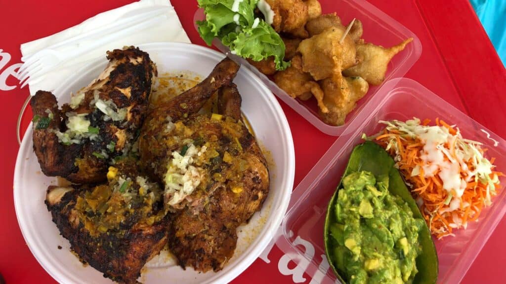 Grilled chicken and accras de morue Martinique served in takeout containers from a local food truck