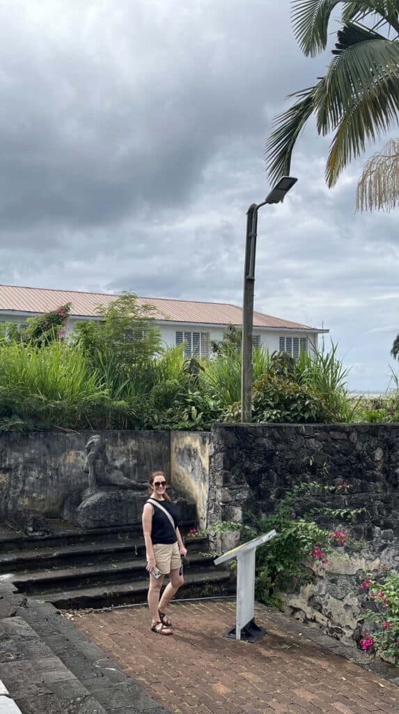 Woman posing beside an overgrown stone wall and mural in historic Saint-Pierre Martinique