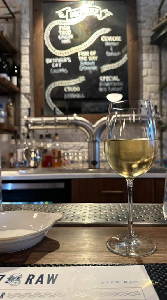 Glass of white wine at 167 Raw oyster bar, a relaxed date night in Charleston for seafood lovers

