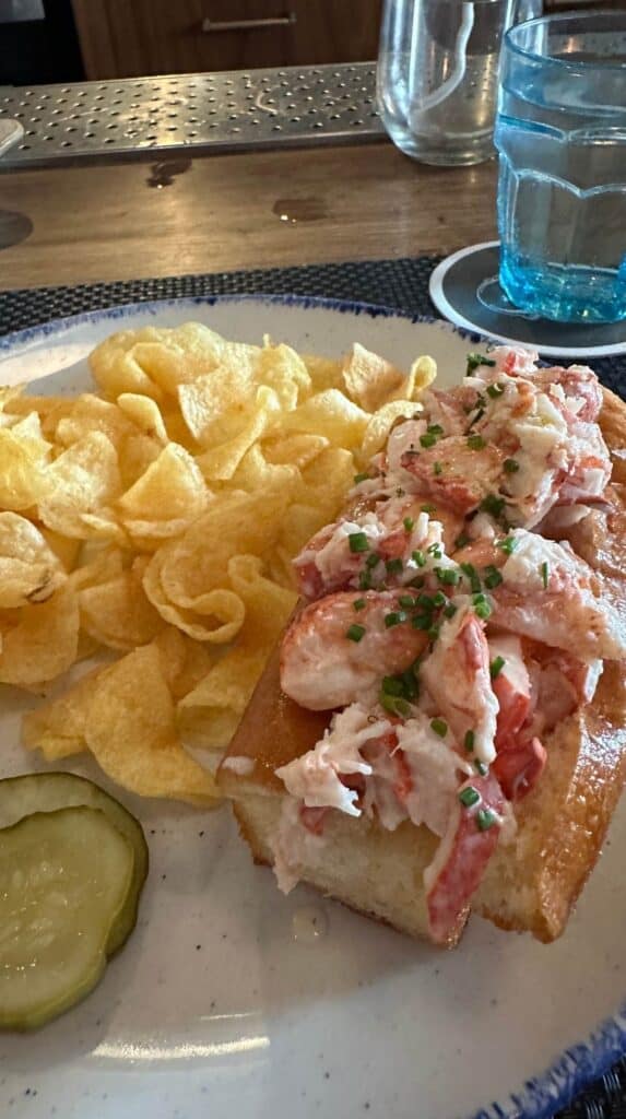 Lobster roll with chips and a pickle at a Charleston oyster bar, a delicious option for things to do in Charleston SC for couples
