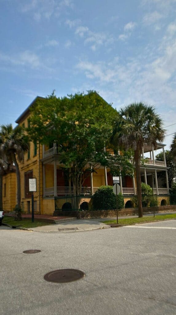 Yellow historic home framed by palms and oaks downtown, worth seeing on a romantic Charleston getaway
