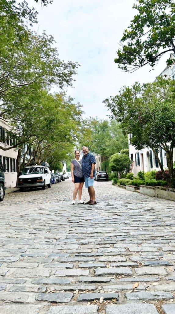 Couple posing together on a cobblestone street lined with historic homes in Charleston for couples
