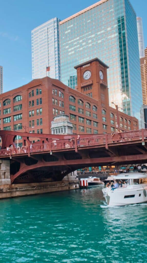 Modern tour yacht slipping beneath a clock tower bridge on an architecture boat tour chicago