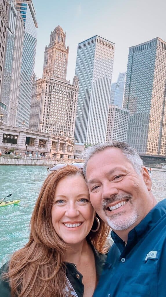 Couple smiling on a best chicago architecture boat tour with the skyline behind them