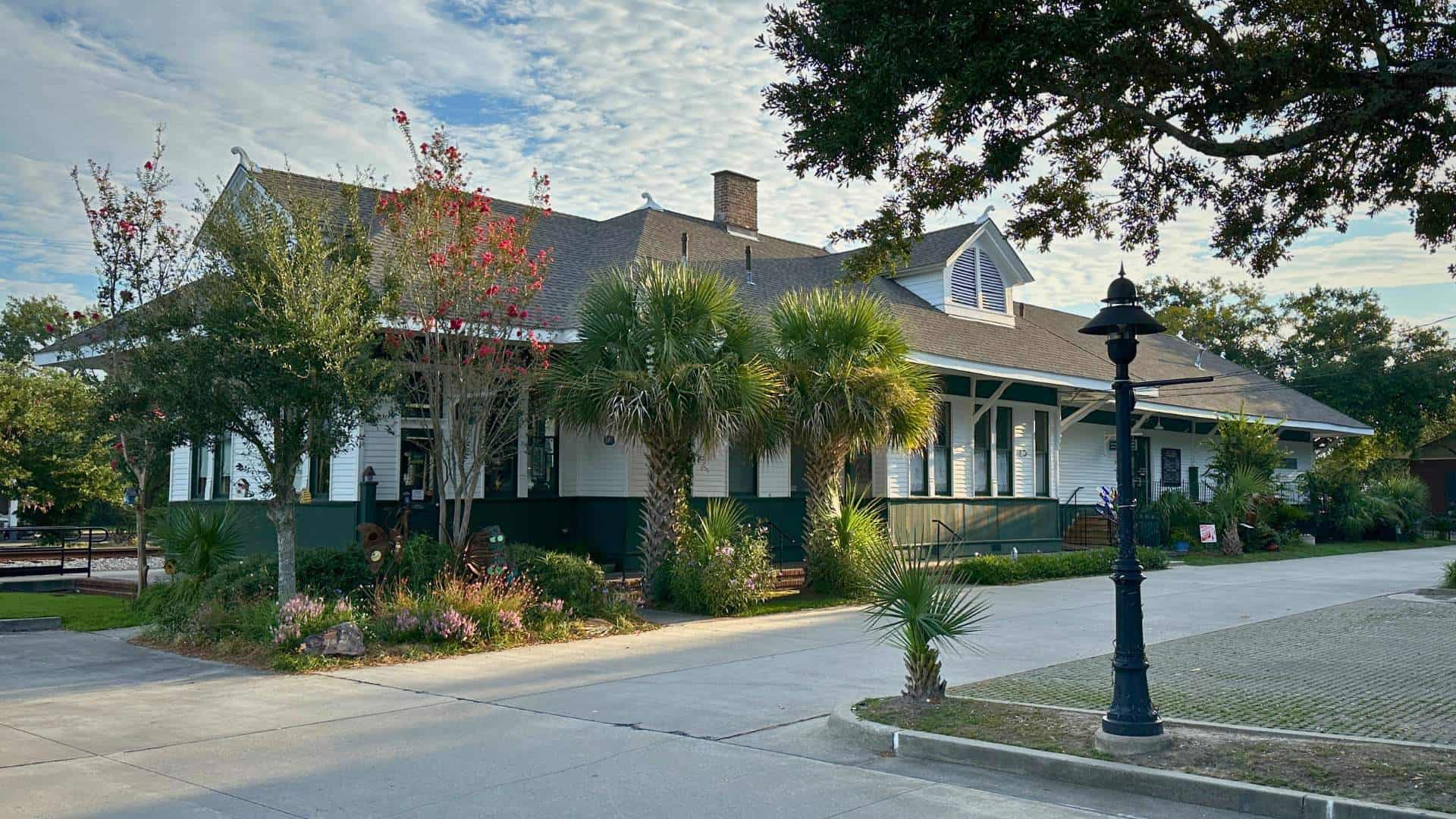 Exterior of the Ocean Springs Visitor’s Center at the historic L and N Train Depot surrounded by palm trees and landscaping in downtown Ocean Springs.