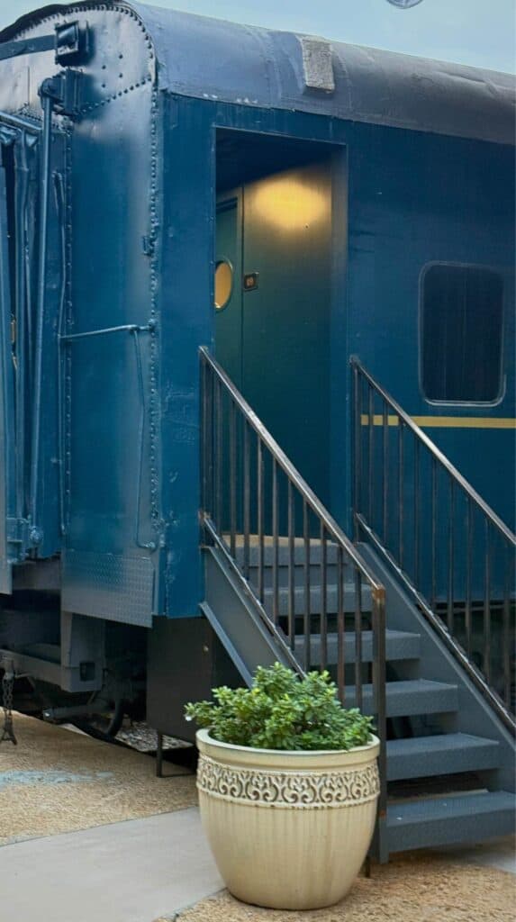 Blue restored train car guest suite with metal stairs and planter outside at The Hotel Chalet at Chattanooga Choo Choo.