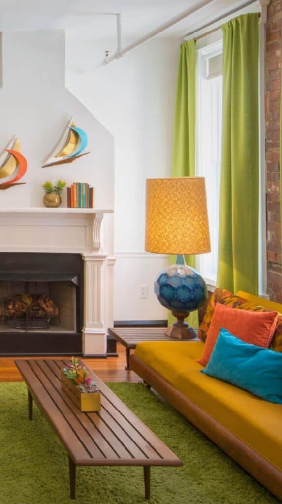 Bright lounge area at The Dwell Hotel with green curtains, colorful pillows, and a modern fireplace creating a playful boutique hotel atmosphere.