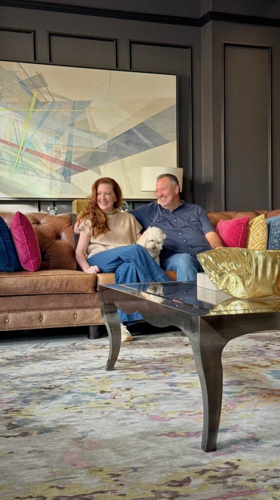 Couple relaxing on a leather sofa inside The Edwin Hotel surrounded by modern art and colorful pillows in an upscale Chattanooga hotel lobby.