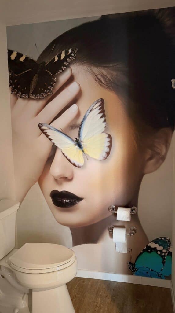 Large mural of a woman’s face with butterflies covering her eyes inside The Edwin Hotel art-filled interior in Chattanooga.