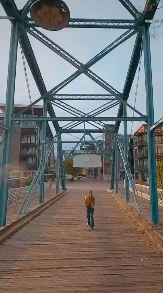 Person walking alone across Chattanooga’s historic Walnut Street Bridge with steel beams framing the wooden walkway.