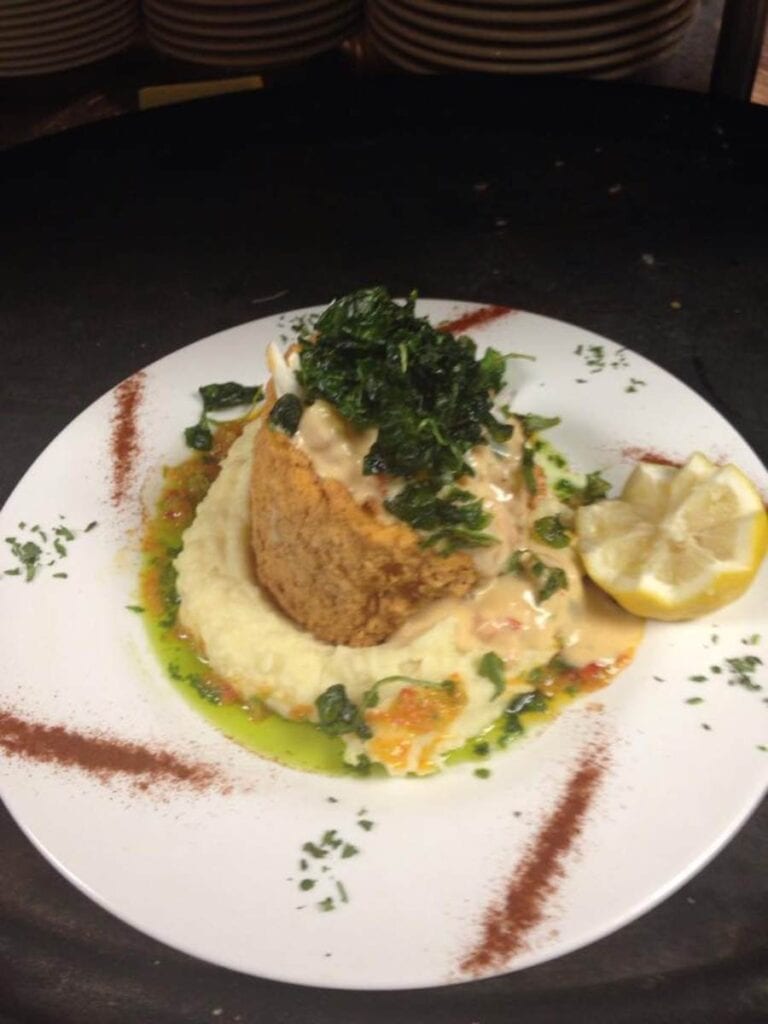 A crab cake over spinach and potatoes at Phoenicia Gourmet, a Gulf Coast answer to where to eat in Ocean Springs downtown.