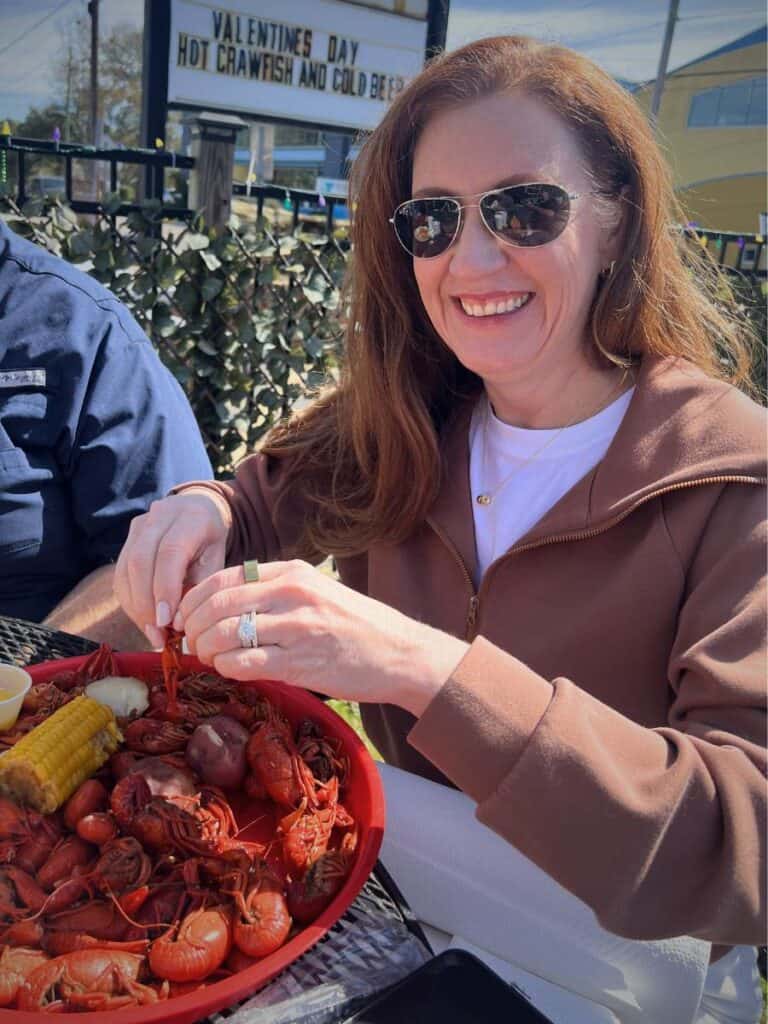 Ashley smiles over a tray of crawfish in the sun, enjoying one of the Best places to eat in Ocean Springs, MS in spring.