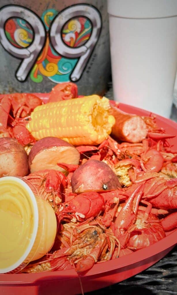 Red tray filled with boiled crawfish, corn, potatoes, and sausage with dipping sauce, showcasing Gulf Coast seafood at restaurants in Ocean Springs MS.