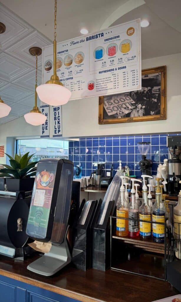 Coffee bar with syrups, espresso machine, and menu board inside Parlor Doughnuts, a trendy breakfast spot in downtown Ocean Springs.