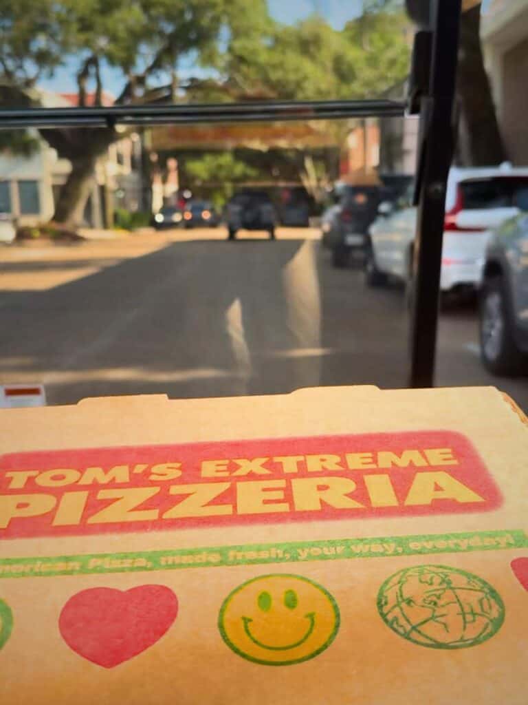 Pizza boxes being carried on a golf cart for takeout, reflecting casual dining and beachside meals in Ocean Springs MS.