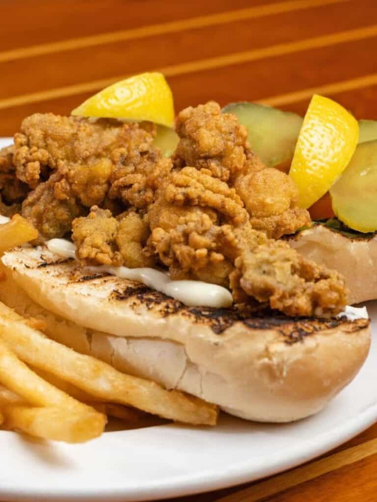 A fried oyster po-boy with fries on a plate, a filling seafood lunch in Ocean Springs worth the short drive out.
