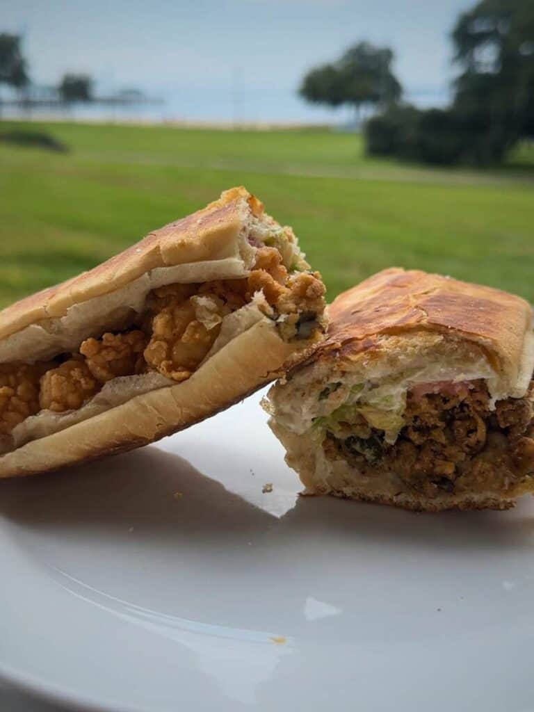 Oyster po boy sandwich overflowing with fried oysters and toppings, a must try when deciding where to eat in Ocean Springs MS.