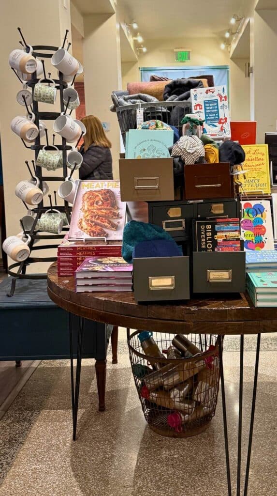 Gift display table at M. Judson Booksellers with books, candles, puzzles, socks, and literary themed accessories.