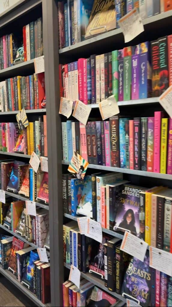 Tall fantasy and fiction bookshelves lined with handwritten staff recommendation notes inside M. Judson Booksellers in Greenville SC.