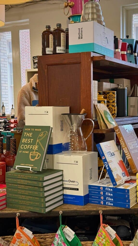 Shelves filled with books, coffee gear, and gifts inside M. Judson Booksellers alongside travel tips and visitor information for the downtown Greenville bookstore.