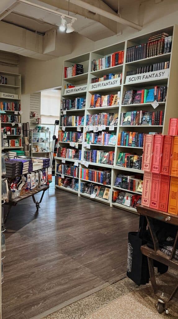 Science fiction and fantasy section inside M. Judson Booksellers with white shelves filled with colorful novels and curated staff picks.