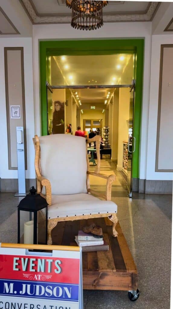 Seating and event space inside M. Judson Booksellers with an “Events at M. Judson” sign near the entrance hallway.