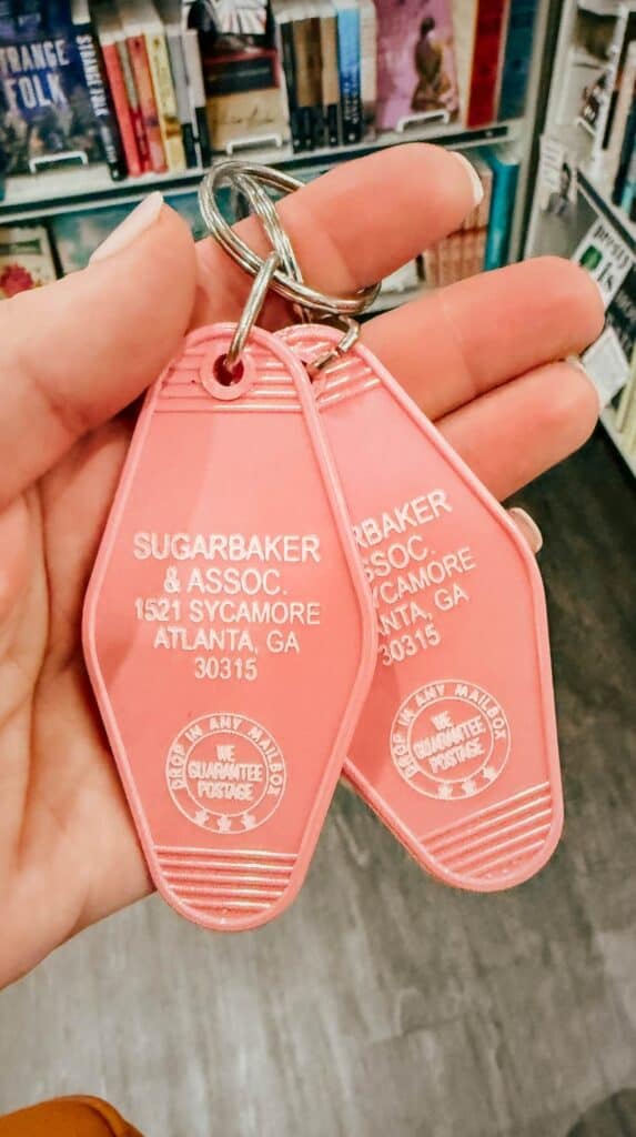 Hand holding pink vintage style motel keychains sold inside M. Judson Booksellers gift section in Greenville SC.