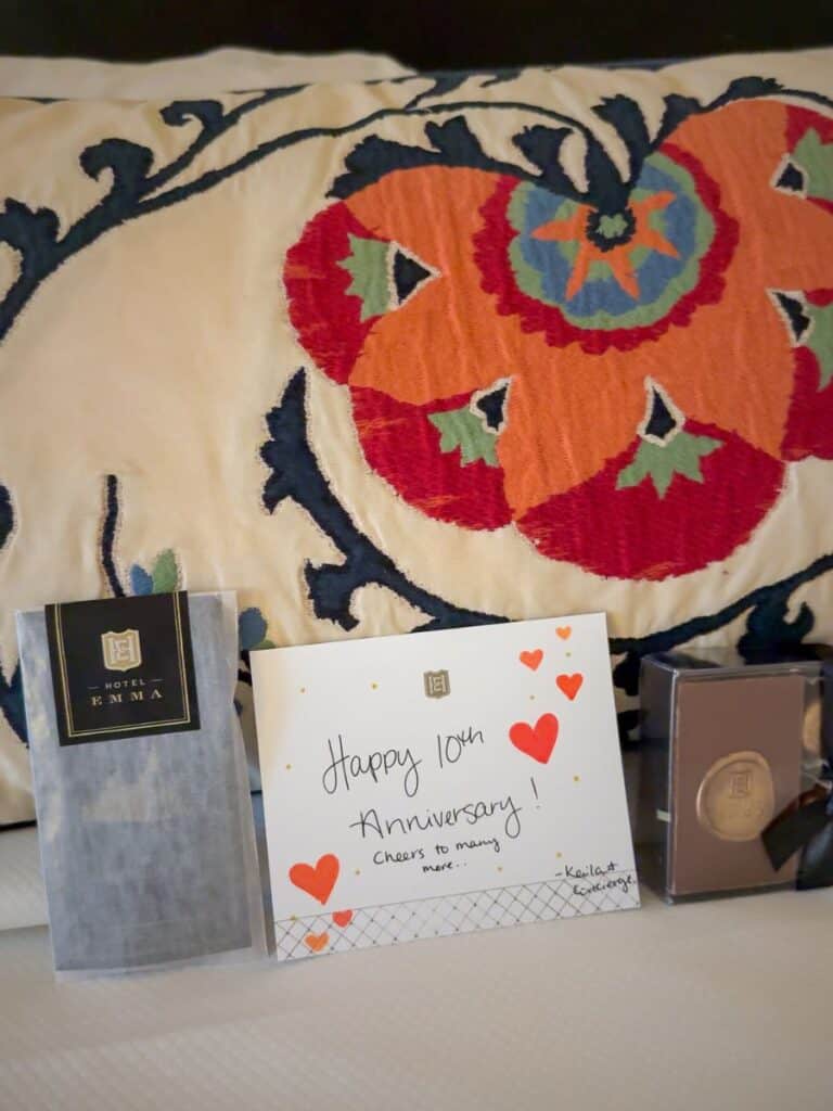 A Hotel Emma anniversary gift with a handwritten card, signature scent, and embroidered pillow