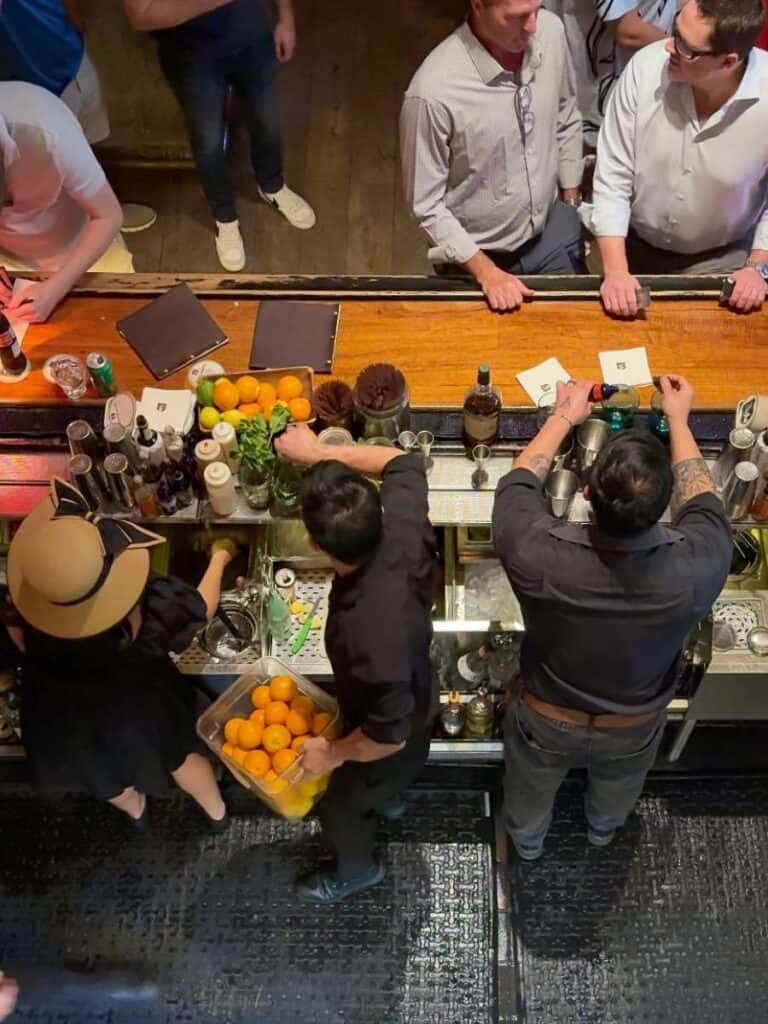 Overhead view of Hotel Emma bartenders mixing craft cocktails with fresh oranges at Sternewirth
