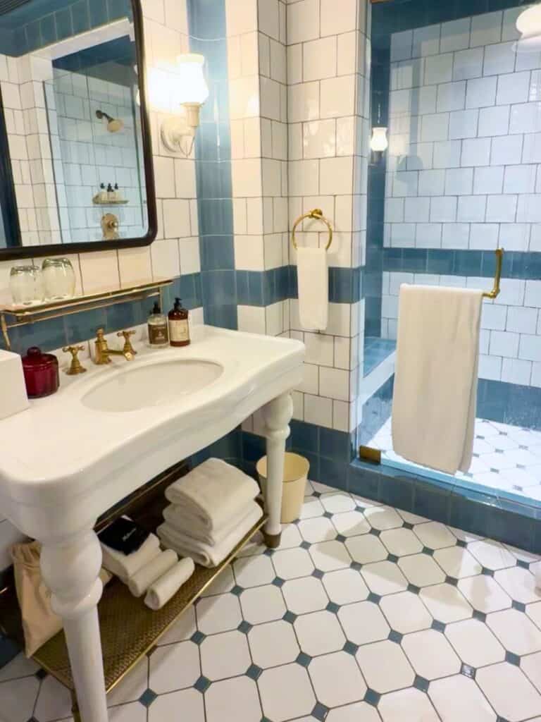 Hotel Emma San Antonio bathroom with a single porcelain vanity, brass fixtures, and blue tile