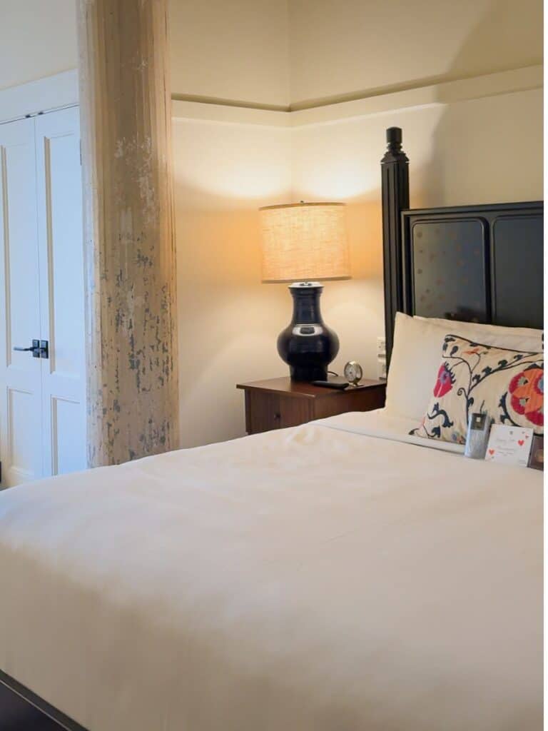 Bold four poster bed dressed in white Frette linens in a Hotel Emma San Antonio Landmark room