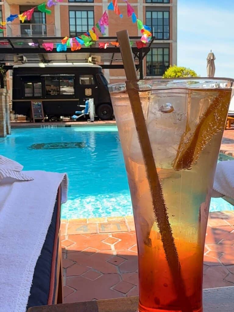 A craft cocktail by the rooftop pool with the Hotel Emma food truck bar in the background