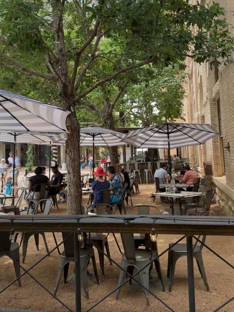 Guests dining under striped umbrellas in the Pearl near Hotel Emma on a warm afternoon