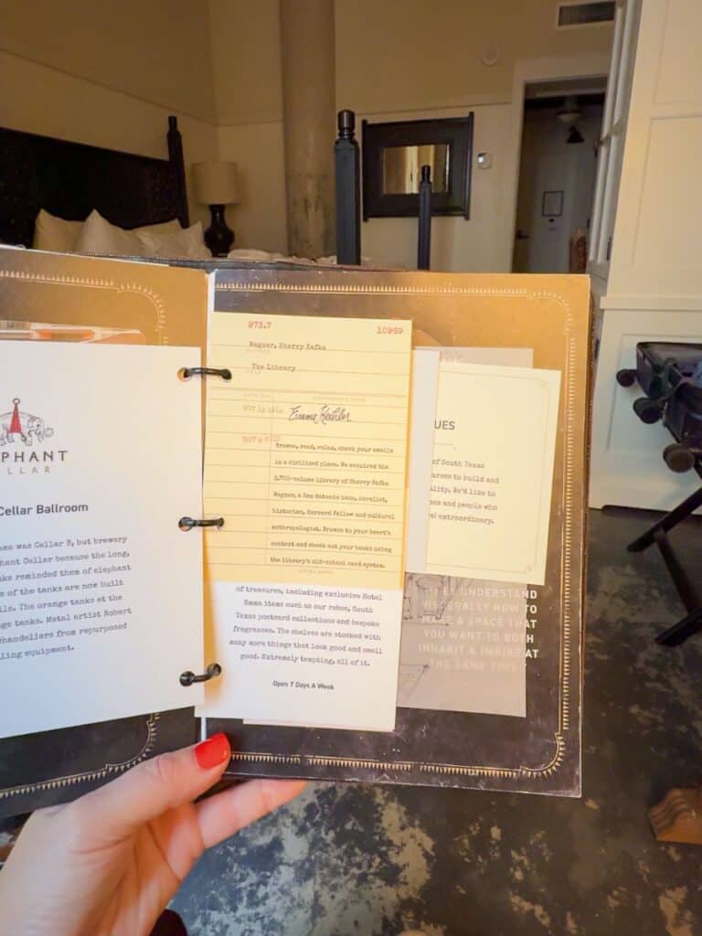 Guest holding the leather-bound in-room guide that Hotel Emma reviews praise for its design