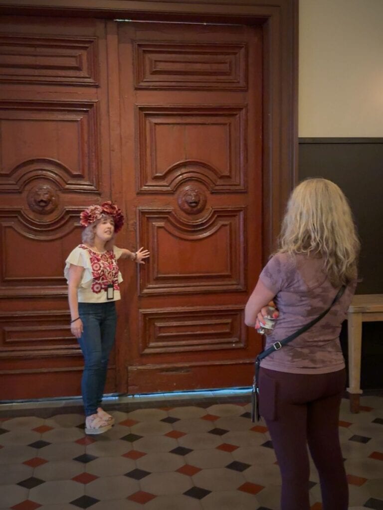 History tour guide at Hotel Emma San Antonio gesturing to carved wood doors with lion details