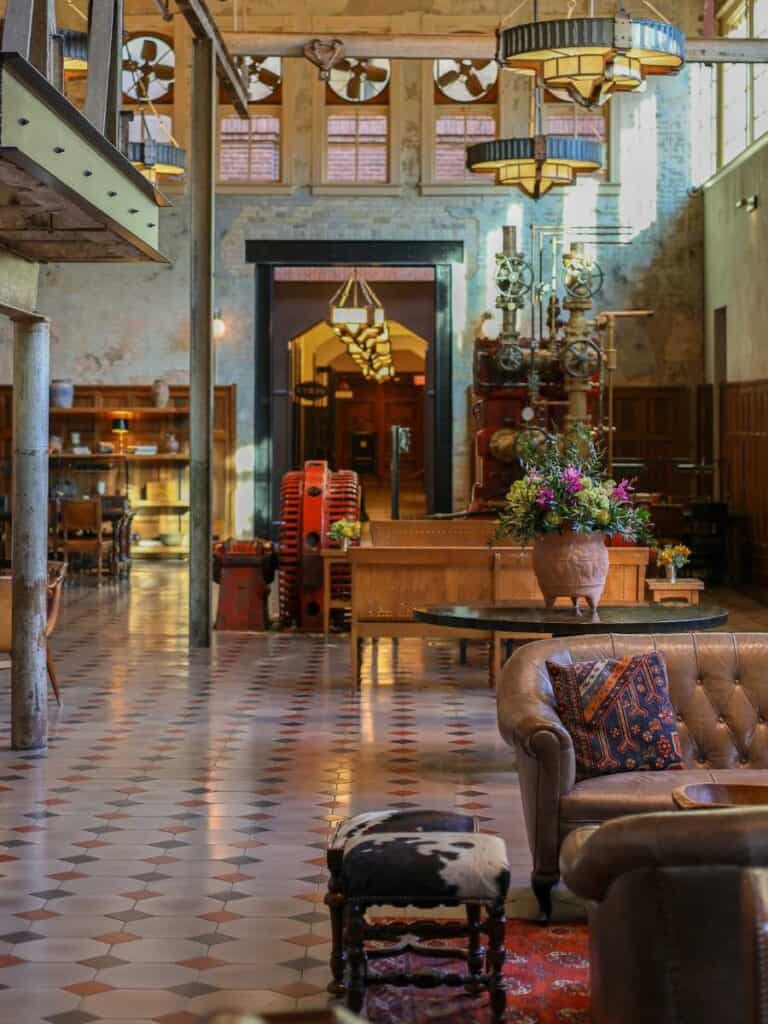 Leather sofa and cowhide stool in the Hotel Emma lobby, with vintage brewing equipment behind