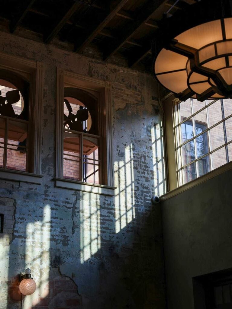 Light pours through tall windows onto exposed brick walls, the kind of design Hotel Emma reviews praise