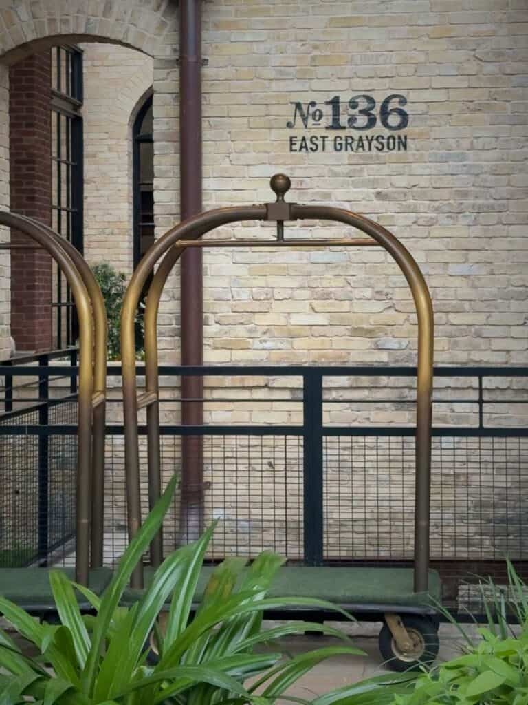 Vintage brass luggage cart, a detail Hotel Emma reviews love, against the No 136 East Grayson wall