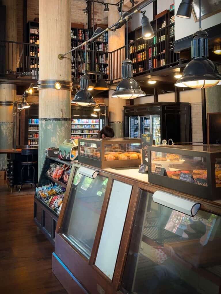 Larder market and cafe at Hotel Emma with a pastry case, pantry goods, and hanging lamps
