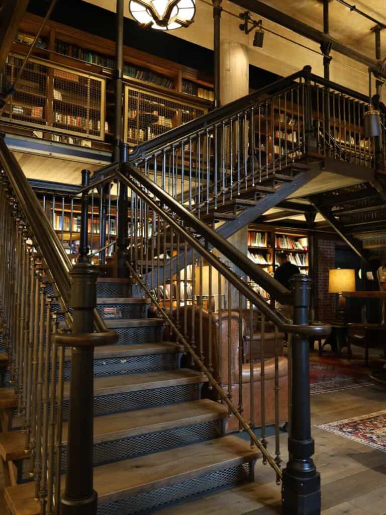 Industrial staircase winding through The Library at Hotel Emma San Antonio, lined with 3,700 books