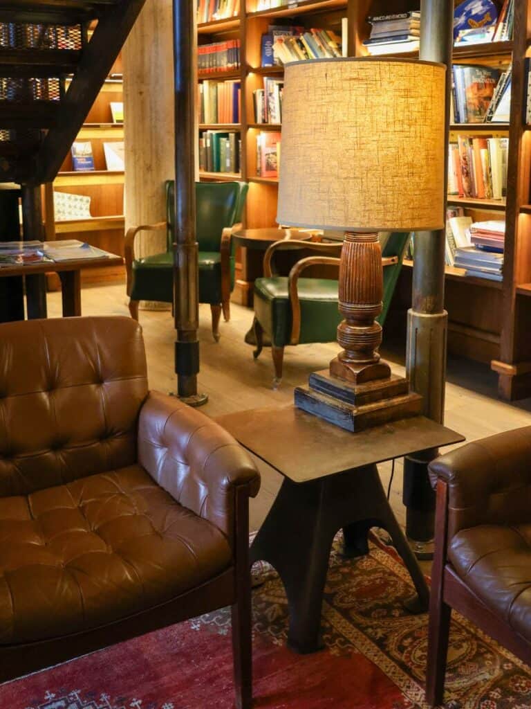 Leather chairs and a warm lamp in The Library, a wind-down spot Hotel Emma reviews recommend