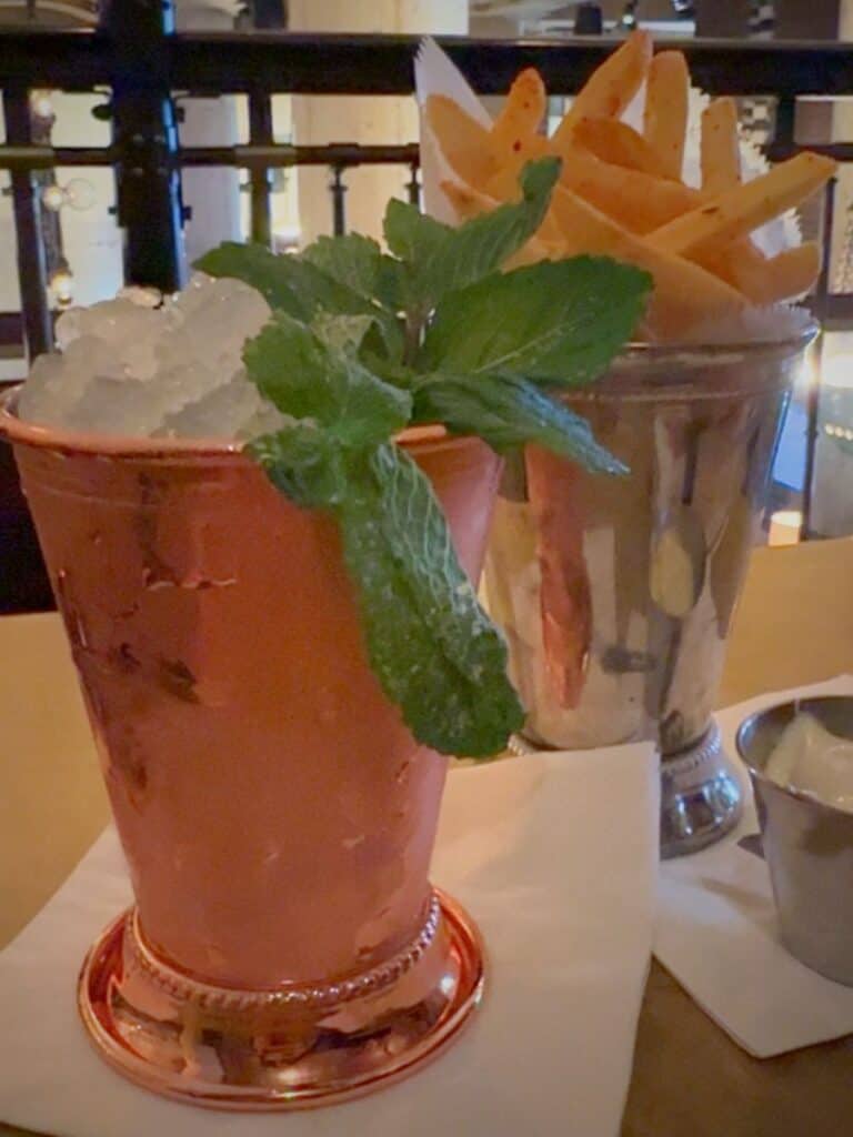 A copper mint julep at Hotel Emma San Antonio's Sternewirth bar served alongside seasoned fries