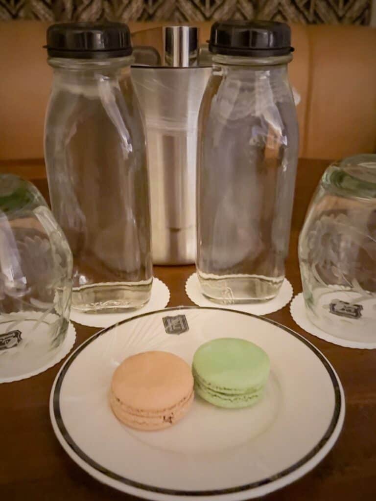 Two glass water bottles and pastel macarons left during Hotel Emma turndown service