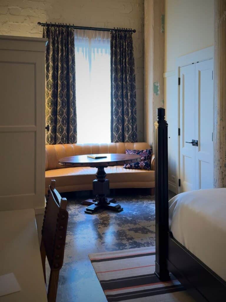 Leather sofa nook by a curtained window in a Hotel Emma room with polished concrete floors
