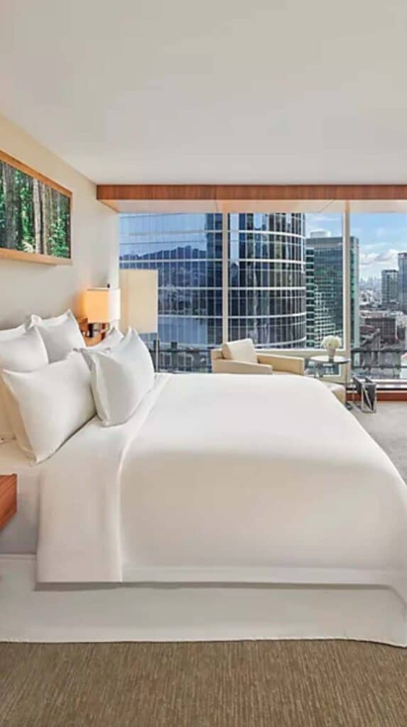 Modern hotel room with floor to ceiling windows overlooking downtown Vancouver near the cruise port.