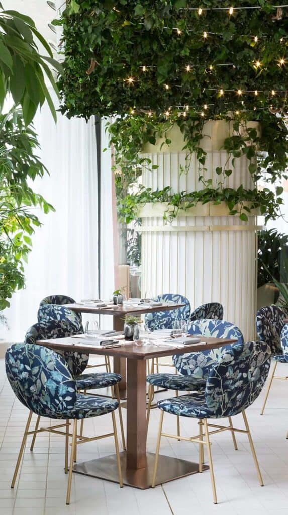 Dining area with round table, patterned chairs, and greenery at a Vancouver hotel near the cruise port.